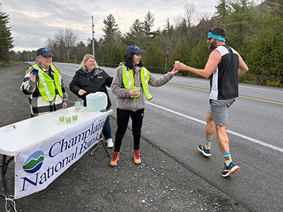 Woman Handing Cup of Water to Runner