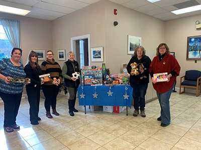 Six Women Holding Toys Next to a Table Stacked with Toys