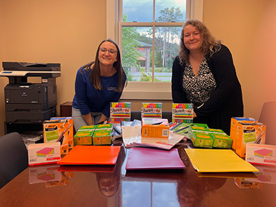 School Supplies Neatly Arranged on a Table with Emily and Gabby Standing Behind it