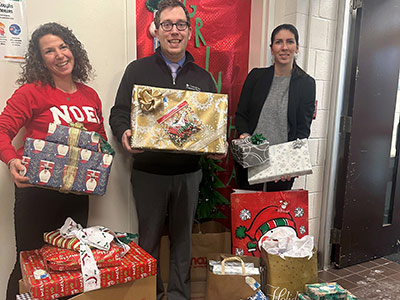 Three People Holding Wrapped Christmas Presents